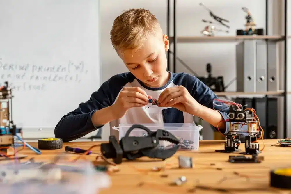 A determined young boy is working on a robot. He is focused and concentrated, and he is clearly enjoying himself.