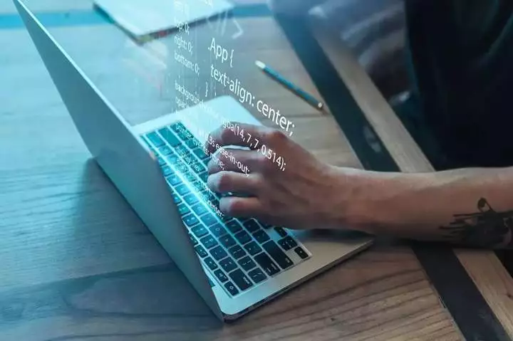 A person's hands are typing on a laptop keyboard.